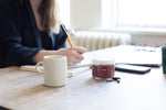 Jar of RELEVATE Brain Health Supplement on desk with woman working